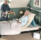 Person sitting  in bed being supported by pillow lifter